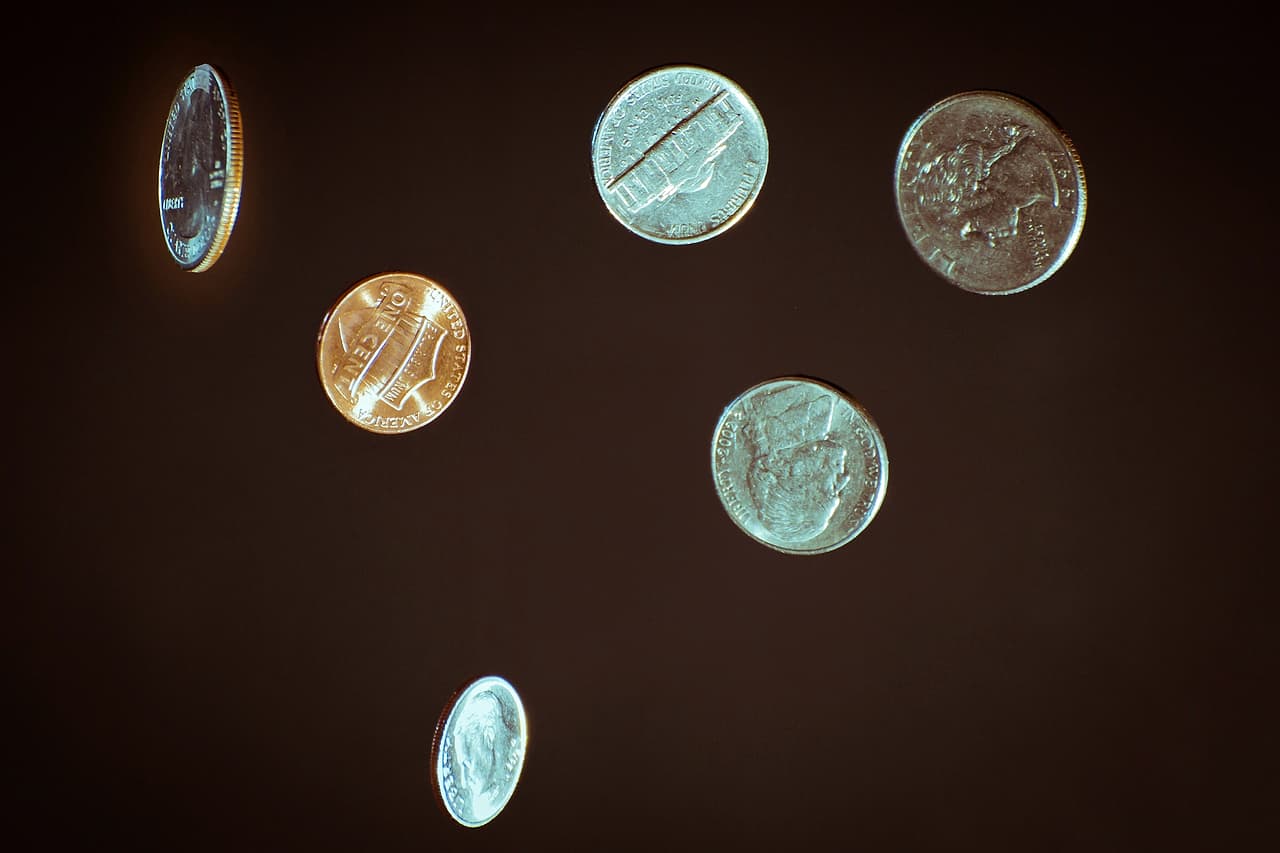A few coins scattered on a dark wooden surface