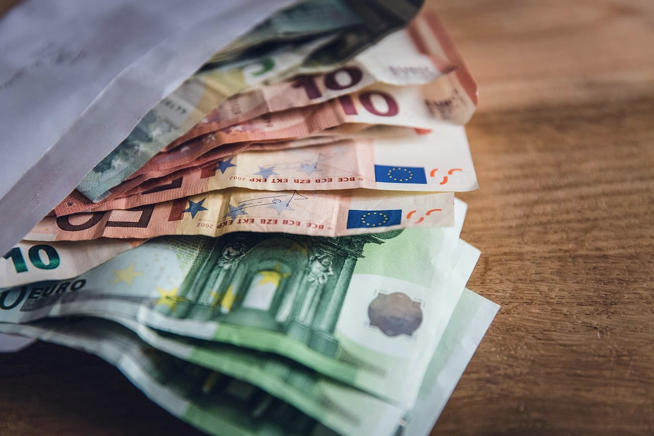 Euro banknotes of several values fanned out on a wooden table