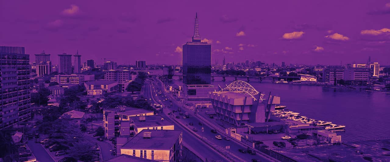 An aerial view of Lagos with high-rise towers, a highway and the lagoon