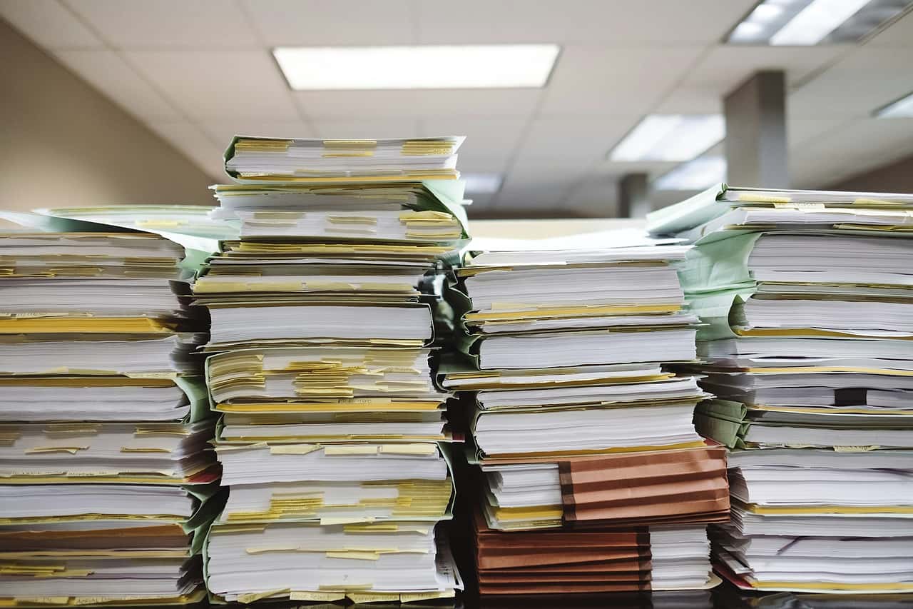 Stacks of paper files and folders piled on office shelves