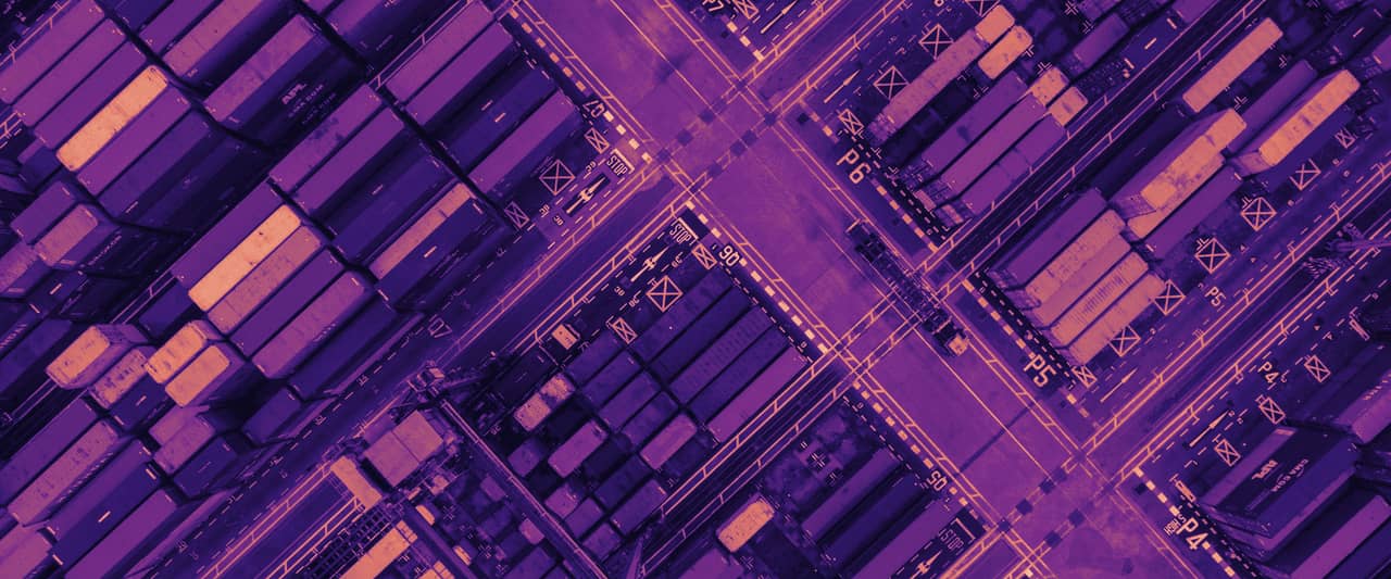 An aerial view of shipping containers stacked in a port yard