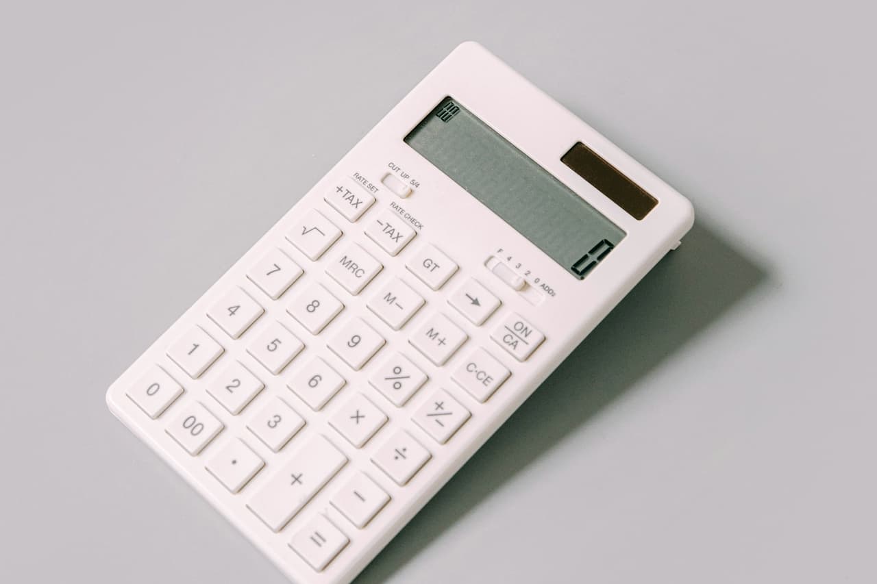 A white calculator lying on a white table