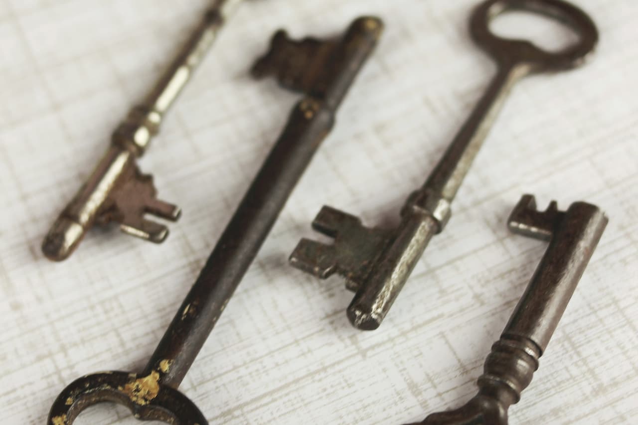 Four old brass keys laid side by side on paper