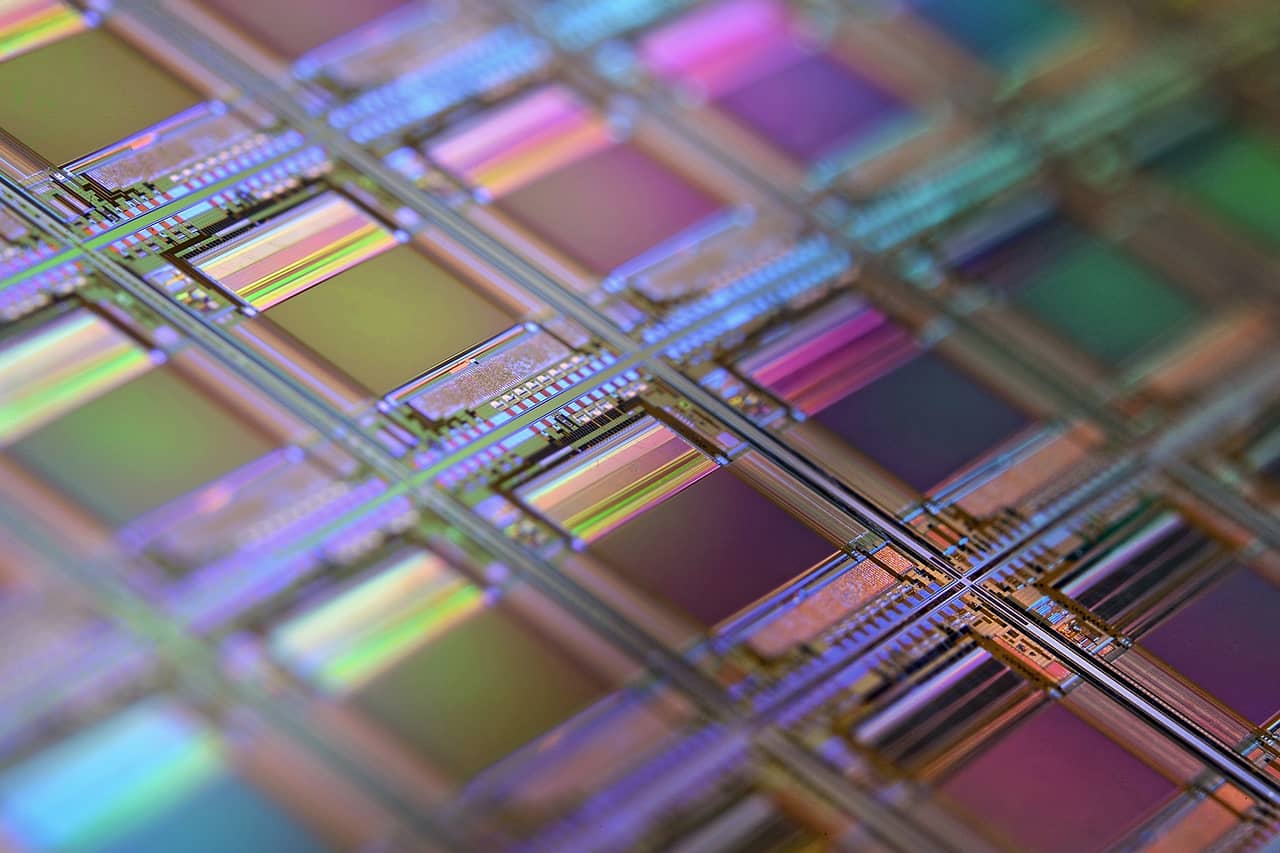 A silicon wafer with a grid of iridescent chip dies