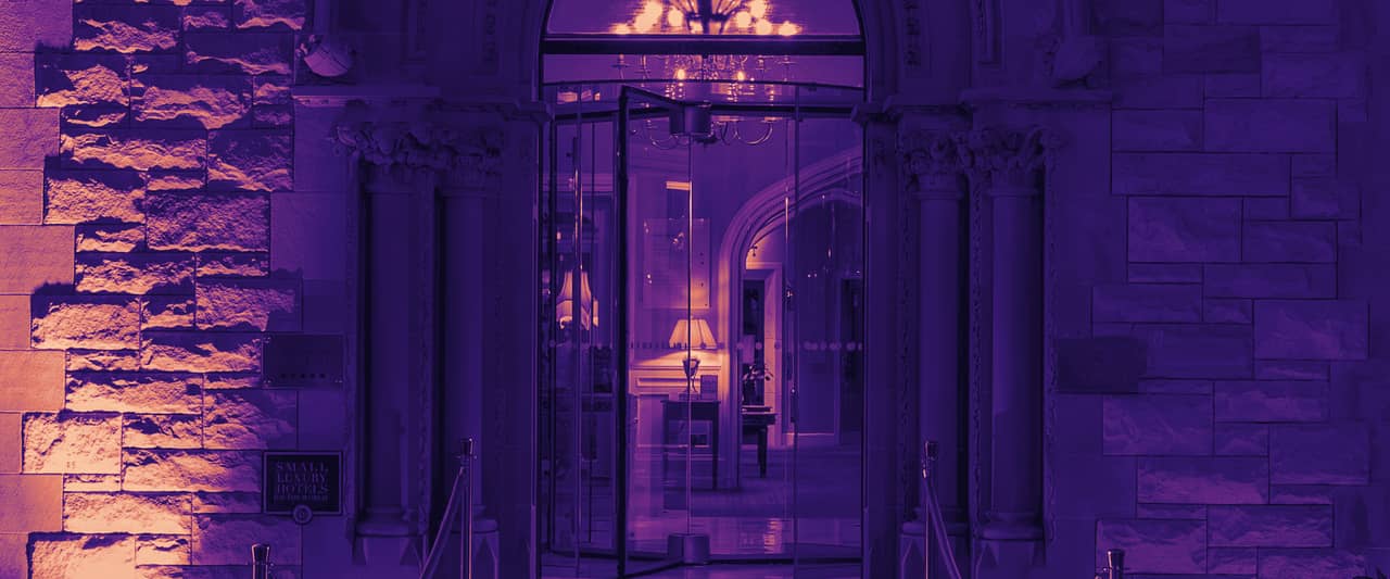 A grand arched entrance with a red carpet between velvet ropes