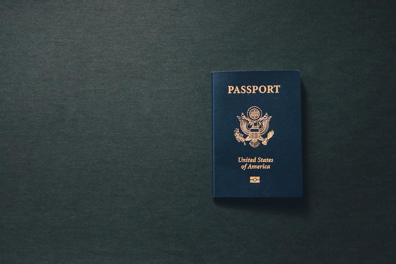 A dark blue passport lying alone on a dark grey surface