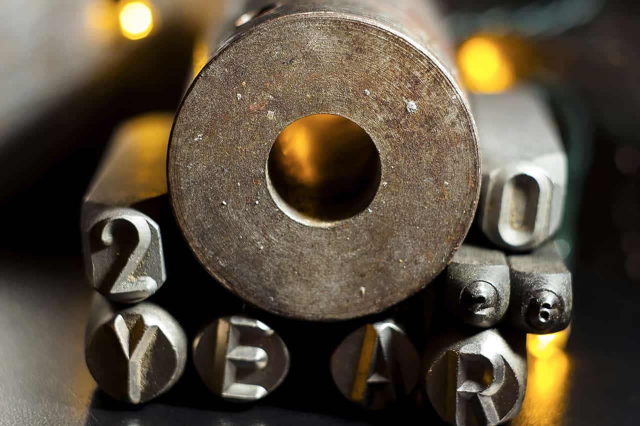 Steel letter punches and a metal die on a dark workbench