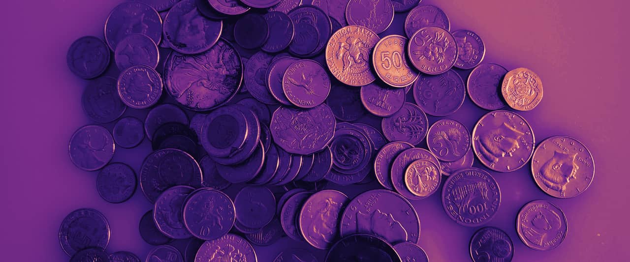 A heap of coins from many countries on a pale surface