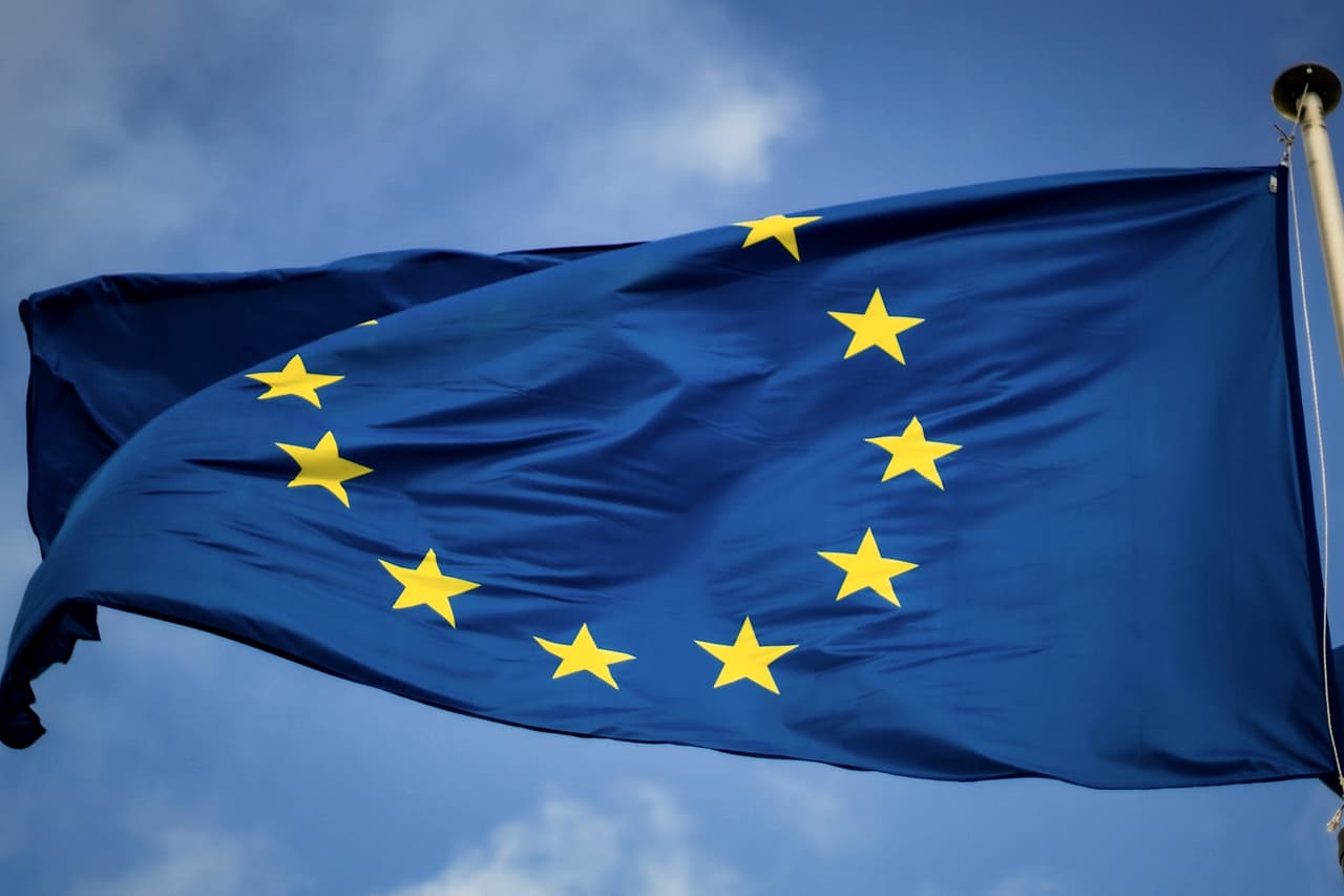 A blue flag with a ring of yellow stars waving on a pole