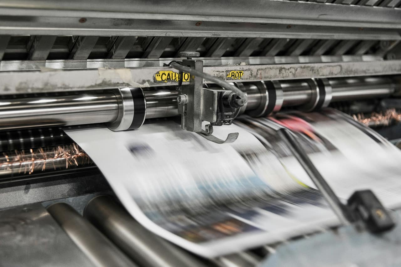Newspapers running at speed through a printing press