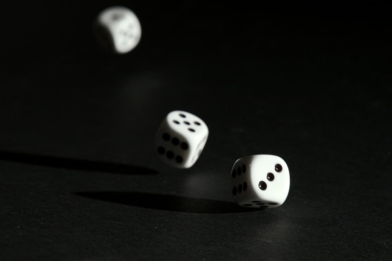 Three white dice falling onto a black surface