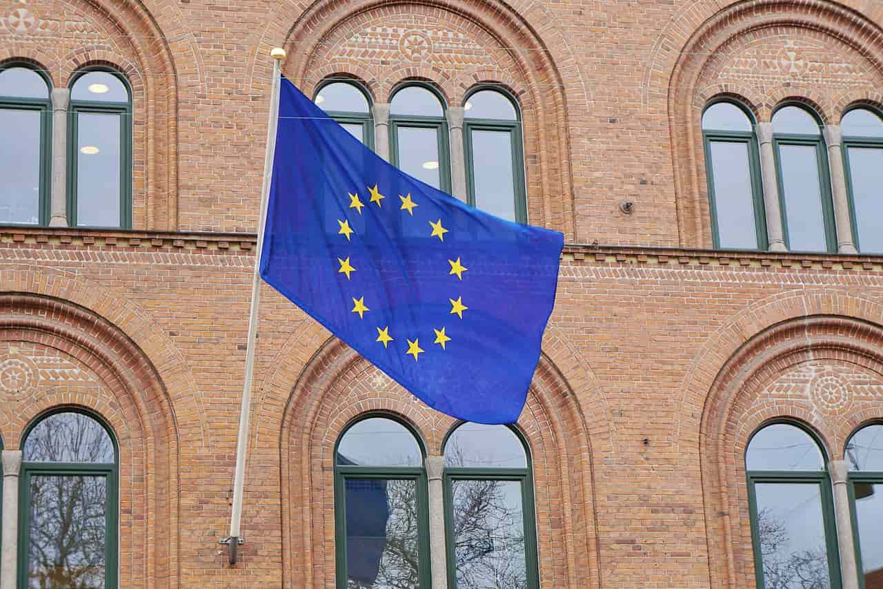 A European Union flag flying in front of a red brick building