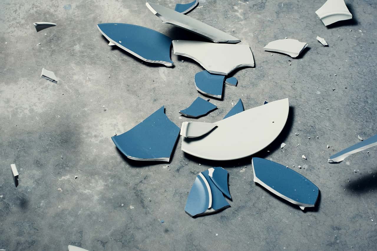 Pieces of a broken blue and white plate on concrete