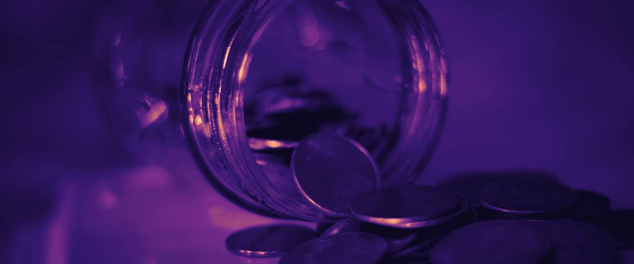 Coins spilling out of a glass jar lying on its side