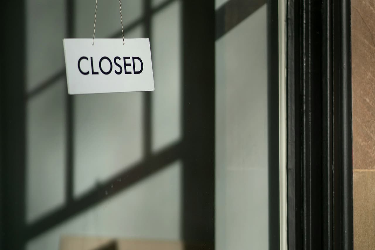 A white Closed sign hanging in a shop window