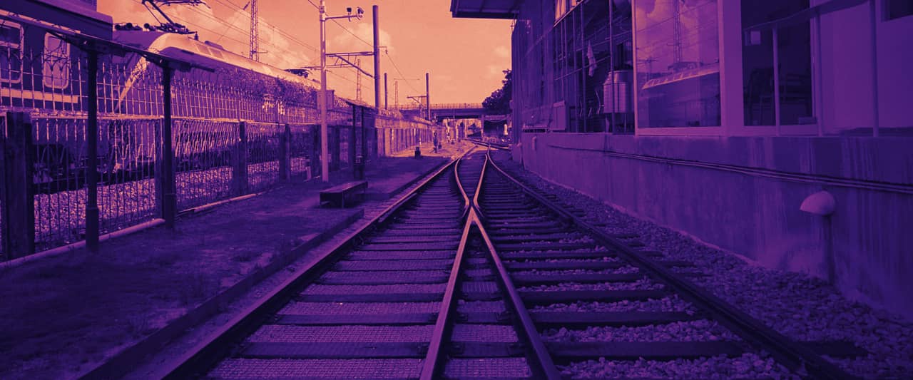 Railway tracks branching apart beside a station platform and a parked train