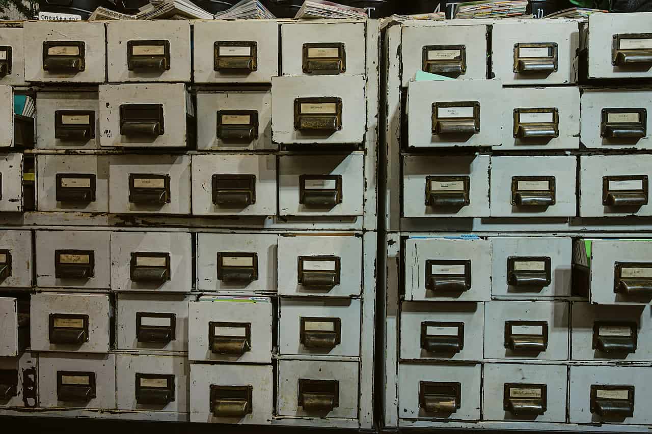 Rows of old metal filing cabinets with labelled drawers