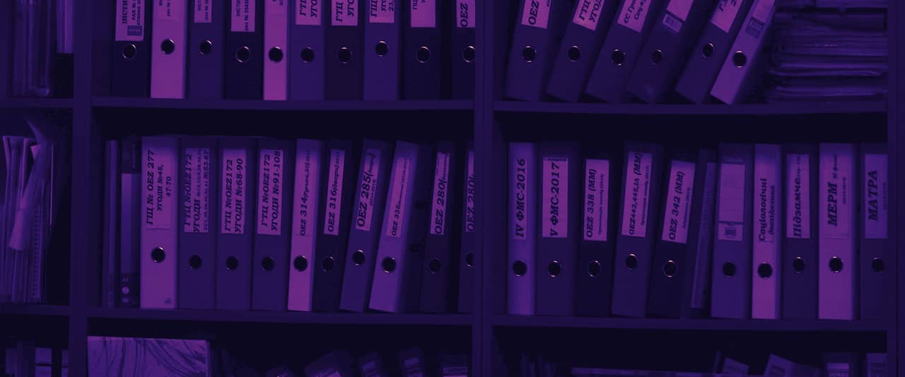 Rows of colourful ring binders on wooden office shelves